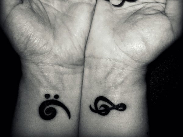 Little wrist tattoo of a bass clef and a treble clef