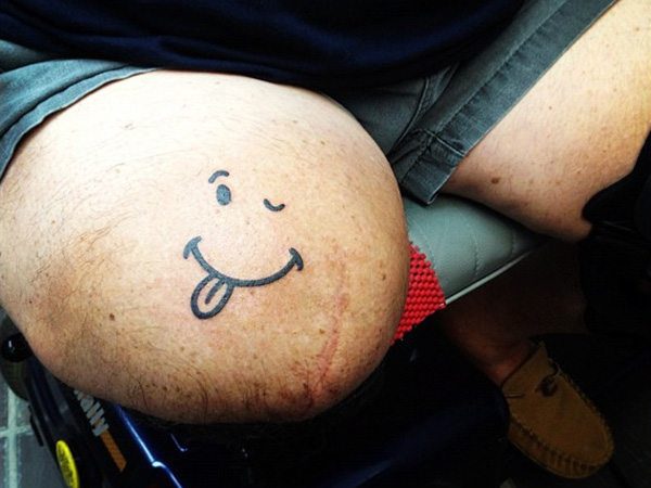 Thigh Smiley Face Tattoo with Tongue Sticking Out