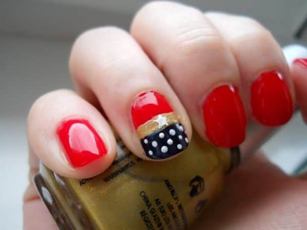 Red Nails with One Nail with a Gold Stripe and Blue Tip Decorated with White Dots