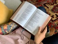 A tattooed man reads a Bible.